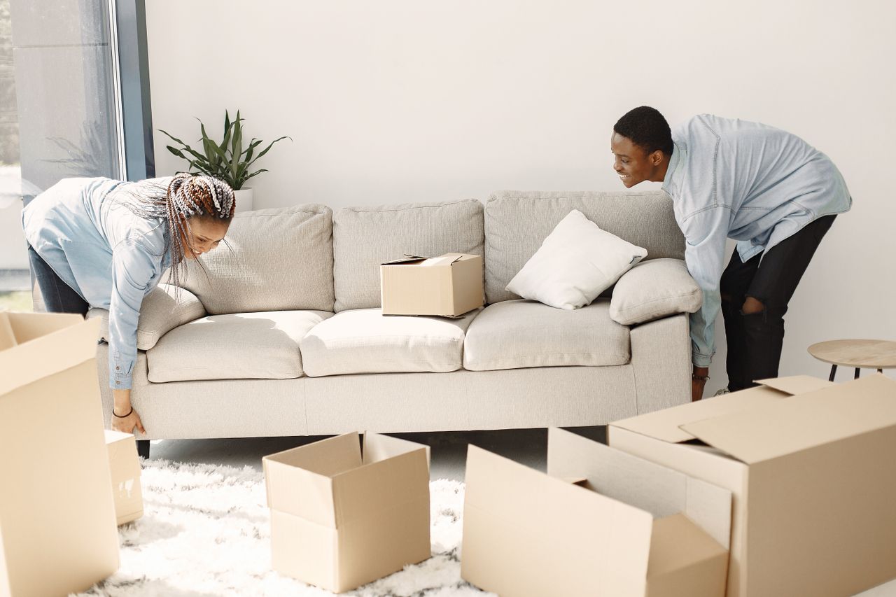 home-hero Happy couple setting up a sofa in their new home surrounded by moving boxes.