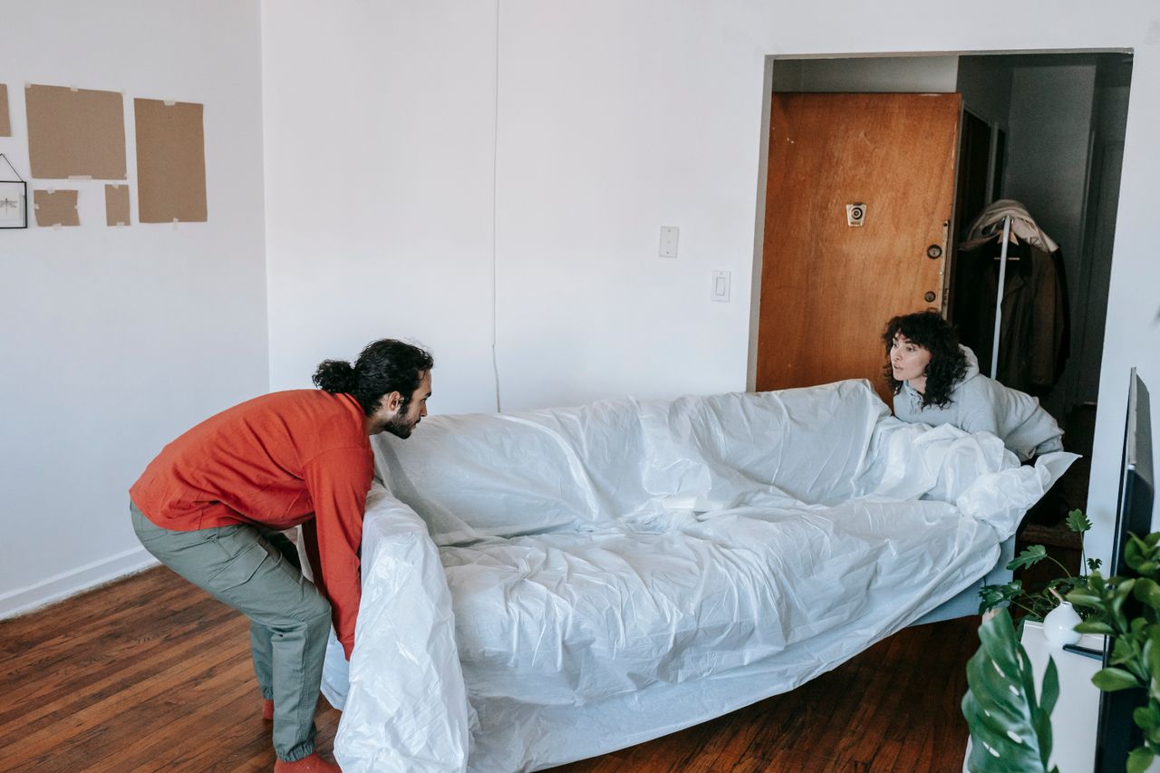 services-05 A couple collaboratively lifting a couch while moving into a new apartment.