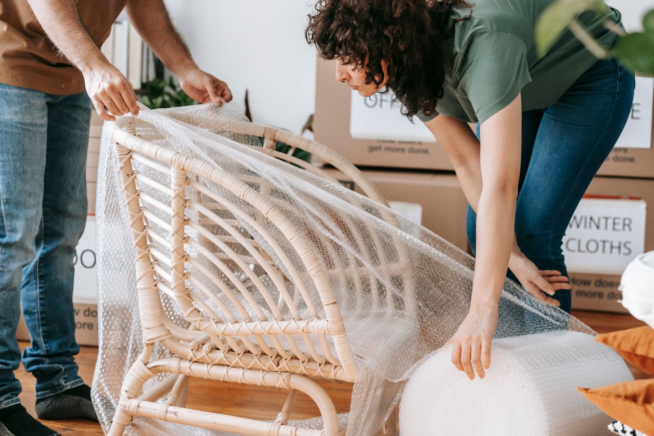 services-06 A couple uses bubble wrap to protect a chair while packing up their home for relocation.